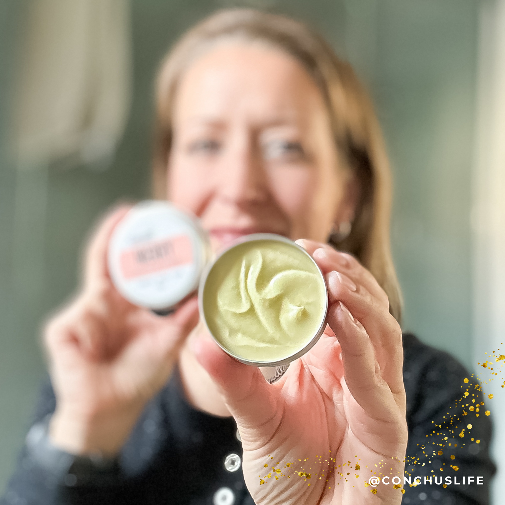 Person holding open tin of CONCHUS MERRY Body Butter showing whipped nourishing texture