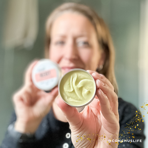 Person holding open tin of CONCHUS MERRY Body Butter showing whipped nourishing texture