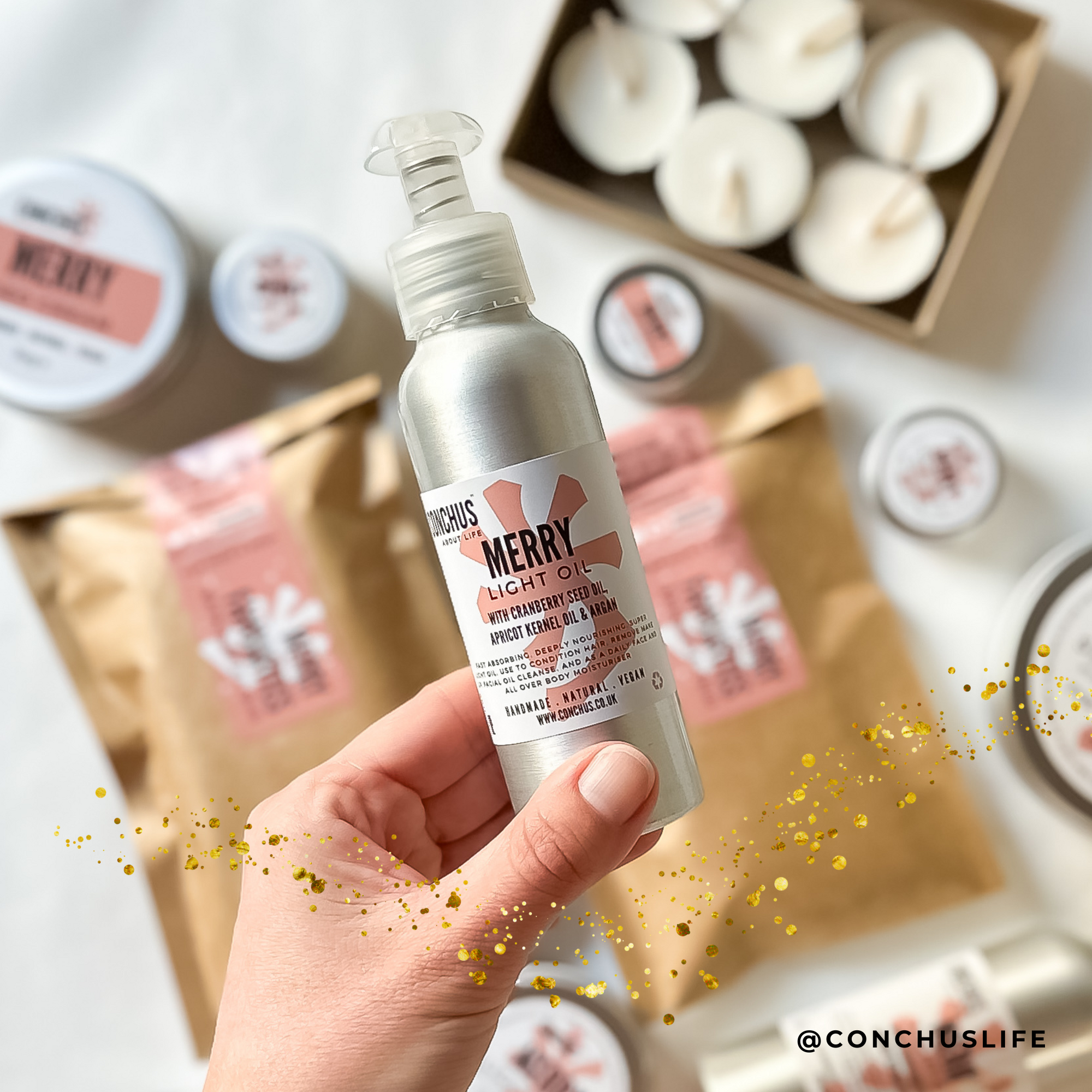 CONCHUS MERRY Light Oil bottle held over festive packaging and skincare gift items. Gift ideas for her. Gift ideas for Mum. 