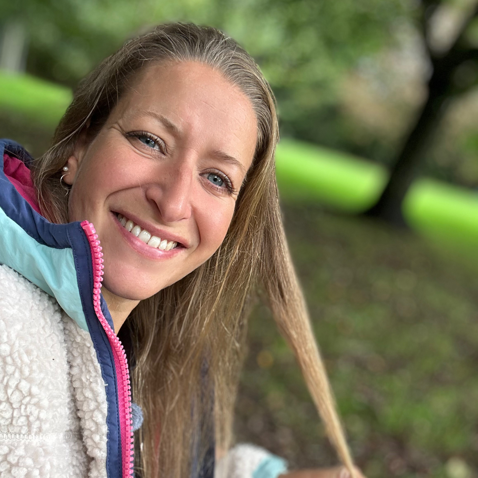Woman smiling outdoors against a green forest background, founder of CONCHUS, a UK handmade vegan skincare brand.
